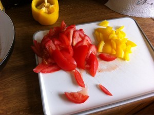 Red and yellow peppers sliced on a white chopping board