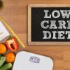 Ketogenic Low Carb Diet One Month in LOW CARB DIET Fitness and weight loss concept dumbbells white scale fruit and tape measure on a wooden table top view free copy space