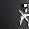 Trying to Stay Low Carb on Long Flights is a Pain Model airplane and cutlery isolated on black background